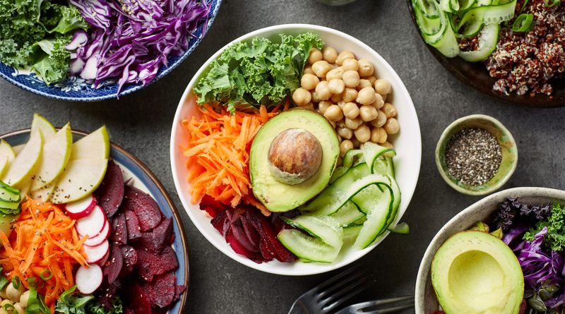 Image of a table full of bowls filled with different fruits and vegetables of various colours to support benefits of being vegan article