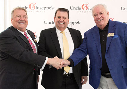The Uncle Giuseppe owners shake hands in front of a back drop
